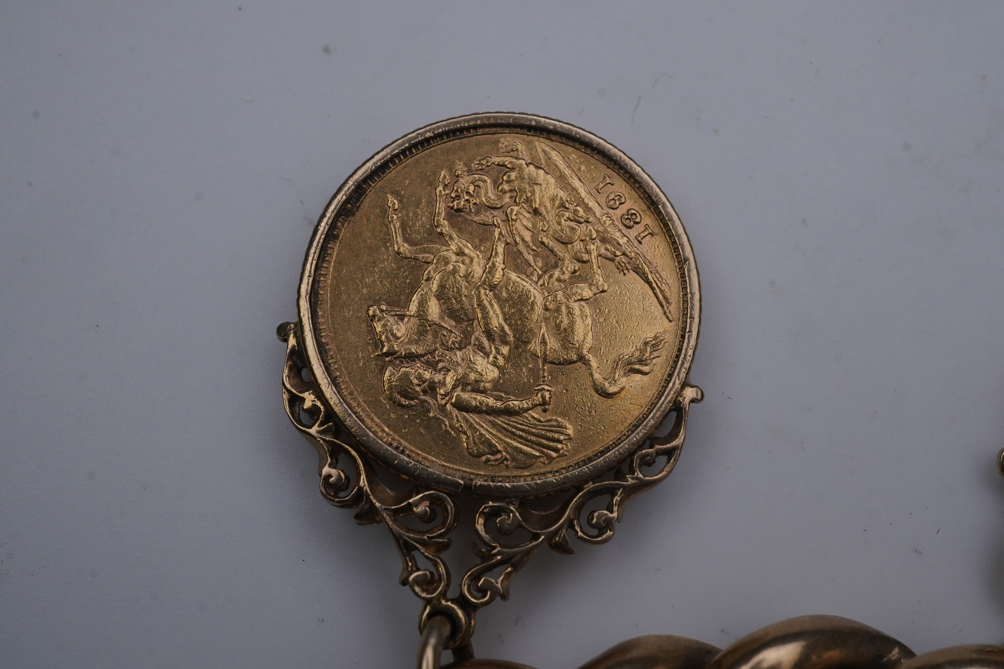 An Edwardian 18ct gold charm bracelet and five gold coin pendants